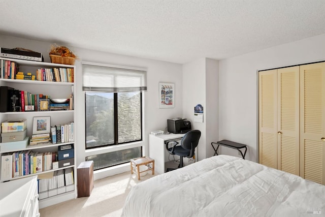 bedroom featuring light colored carpet, a textured ceiling, and a closet