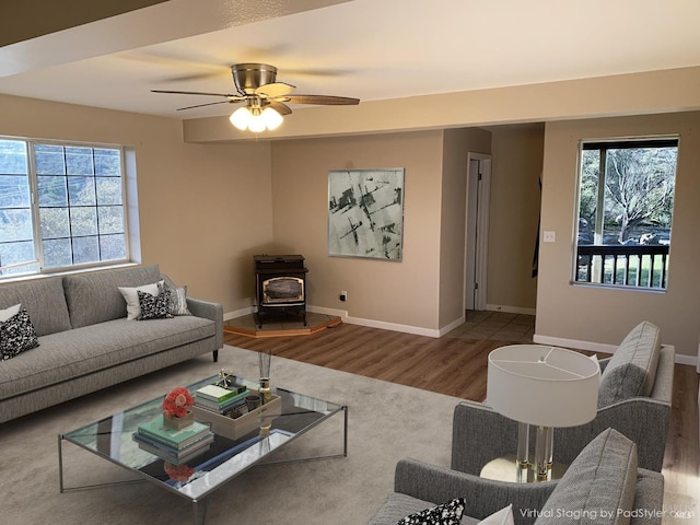 living room featuring hardwood / wood-style flooring, ceiling fan, and a wood stove