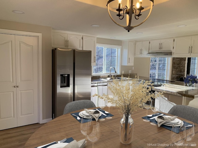 kitchen with stainless steel appliances, white cabinetry, hanging light fixtures, and kitchen peninsula