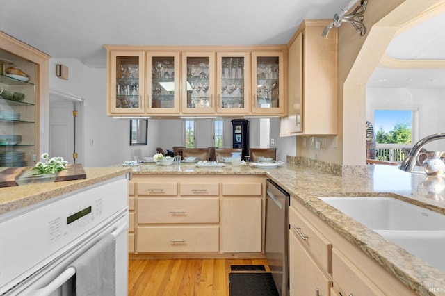 kitchen with light brown cabinets, sink, light hardwood / wood-style flooring, stainless steel dishwasher, and kitchen peninsula