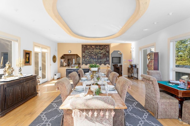 dining area featuring french doors, a tray ceiling, and light hardwood / wood-style floors