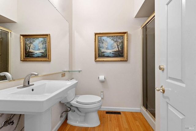 bathroom with sink, toilet, a shower with door, and hardwood / wood-style flooring