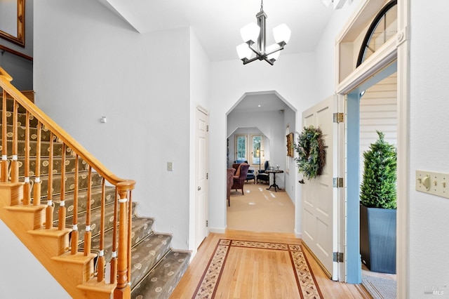 entrance foyer featuring hardwood / wood-style floors, a towering ceiling, and a notable chandelier