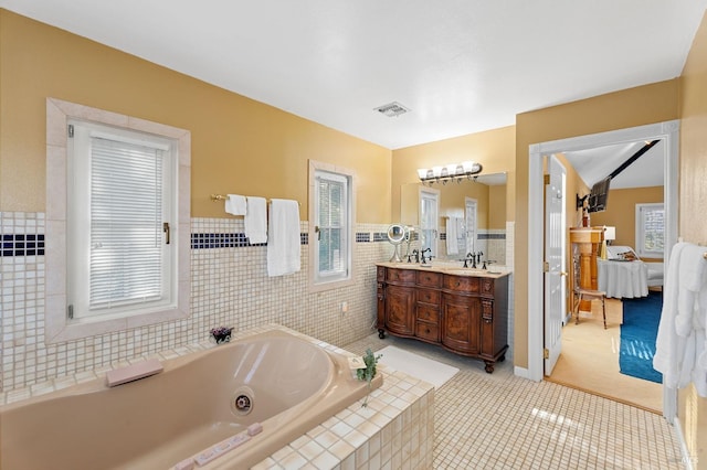 bathroom with vanity, tiled bath, tile patterned floors, and tile walls