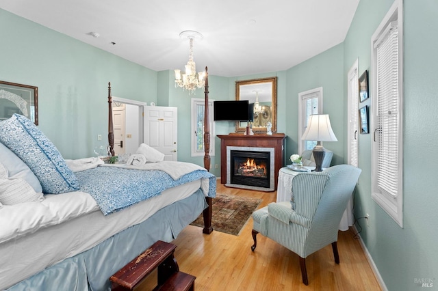 bedroom featuring an inviting chandelier, multiple windows, and light hardwood / wood-style flooring