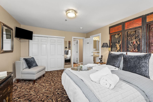 bedroom featuring ensuite bathroom, dark carpet, and a closet