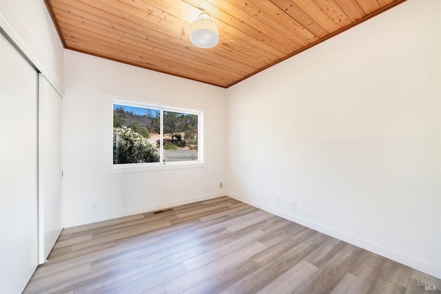 unfurnished bedroom featuring light hardwood / wood-style flooring, a closet, crown molding, and wood ceiling