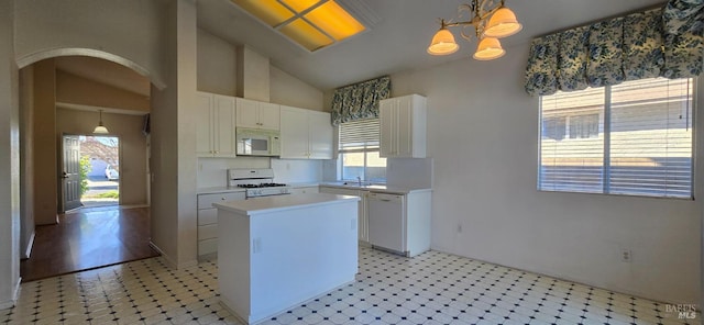 kitchen with a center island, white cabinetry, white appliances, and hanging light fixtures