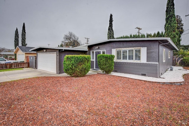 view of front of property featuring a garage, driveway, fence, and stucco siding