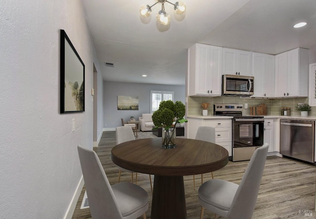 dining area with light wood-style floors, recessed lighting, visible vents, and baseboards