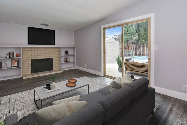 living room with visible vents, a fireplace, baseboards, and wood finished floors