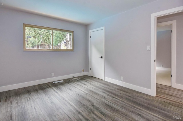 spare room with visible vents, baseboards, and wood finished floors