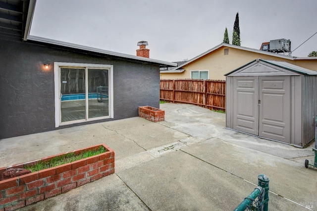 view of patio with an outbuilding, a shed, cooling unit, and fence