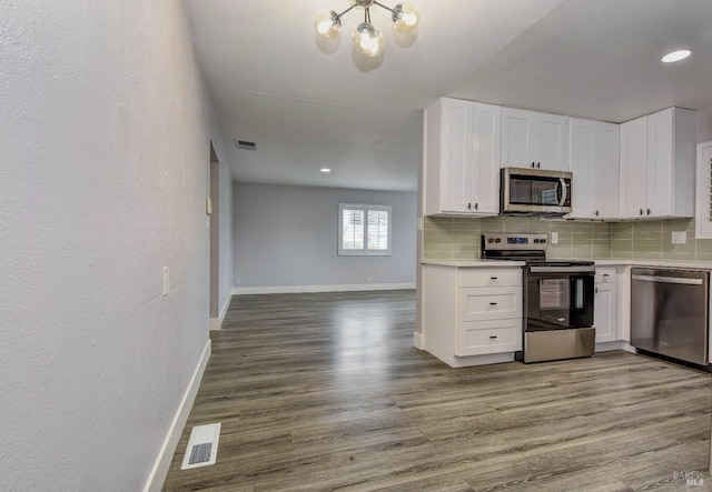 kitchen featuring stainless steel appliances, tasteful backsplash, visible vents, white cabinets, and wood finished floors