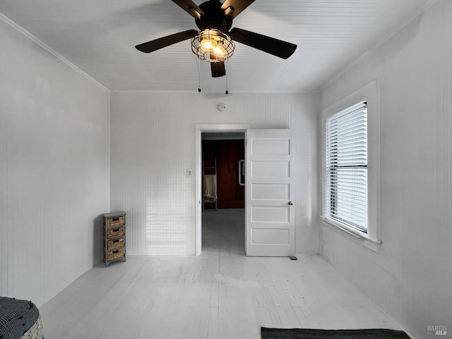 empty room featuring ceiling fan, crown molding, and wood-type flooring