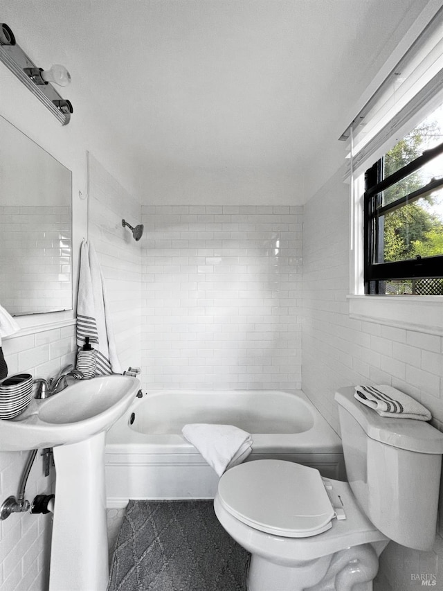 bathroom featuring backsplash, toilet, tiled shower / bath, and tile walls