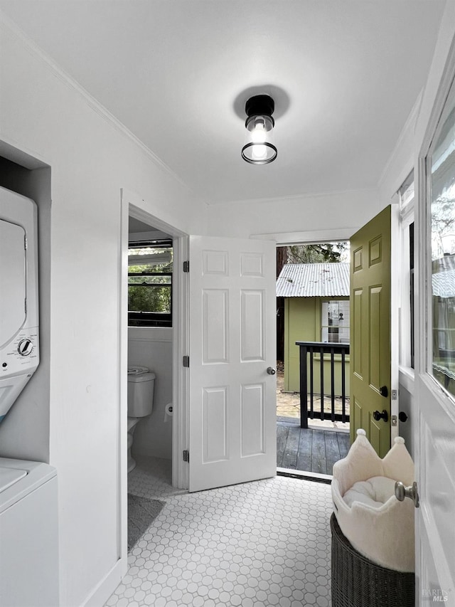 interior space featuring stacked washer / dryer, ornamental molding, and toilet