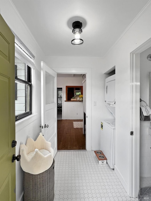 clothes washing area featuring stacked washing maching and dryer and ornamental molding