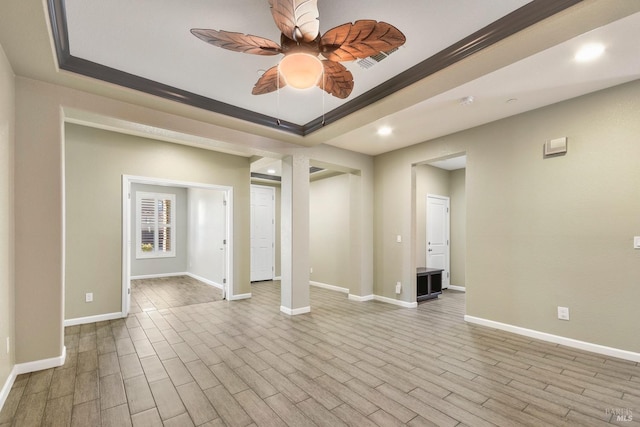 spare room featuring ceiling fan, a raised ceiling, light wood-type flooring, and crown molding