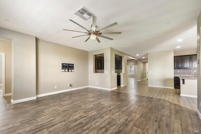 unfurnished living room featuring ceiling fan and a textured ceiling