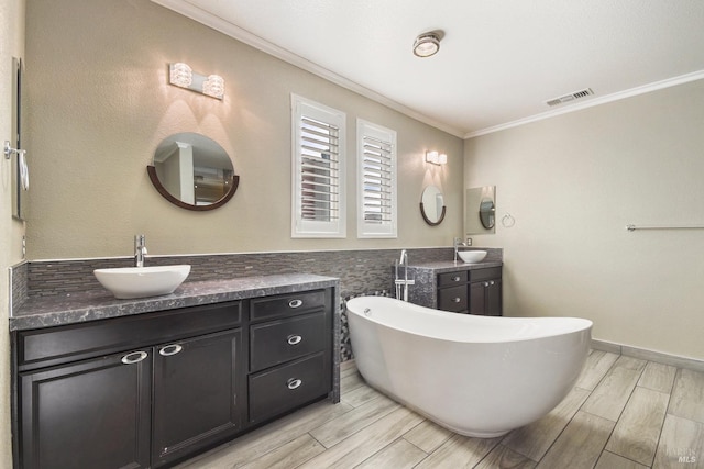 bathroom featuring a bathing tub, vanity, and ornamental molding