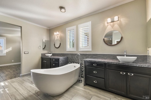 bathroom with a tub to relax in, vanity, and ornamental molding