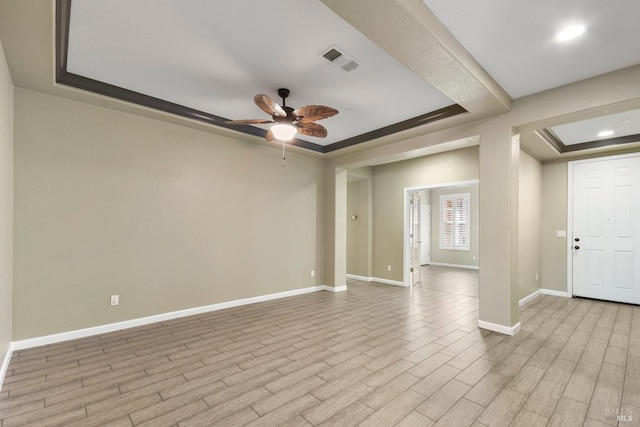 unfurnished room featuring a raised ceiling and ceiling fan