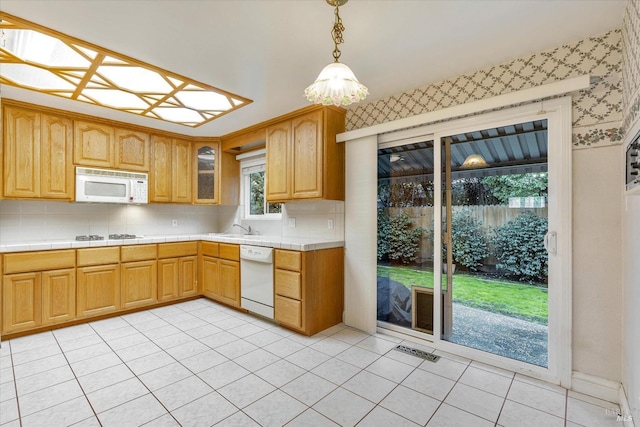 kitchen featuring tasteful backsplash, white appliances, sink, decorative light fixtures, and light tile patterned flooring