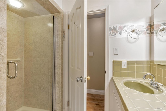 bathroom featuring hardwood / wood-style flooring, a shower with shower door, and sink