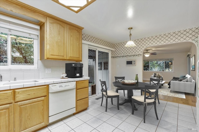 kitchen featuring ceiling fan, tile counters, dishwasher, a healthy amount of sunlight, and hanging light fixtures