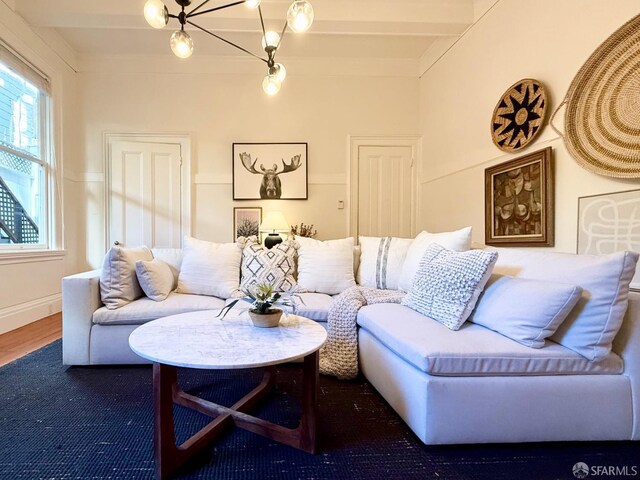 living room featuring beamed ceiling, hardwood / wood-style floors, and a notable chandelier