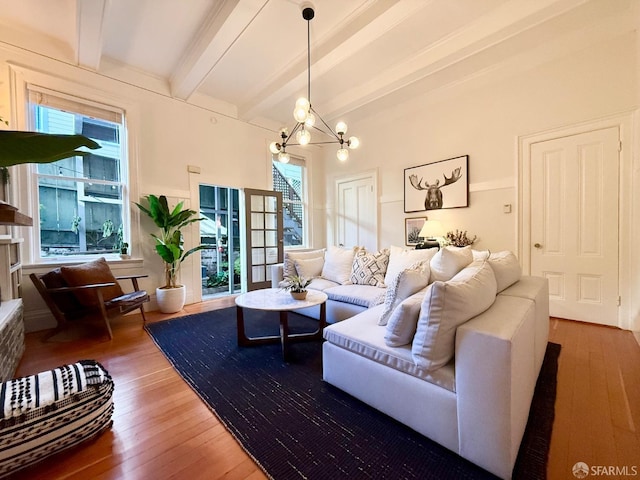 living area with wood finished floors, beam ceiling, and an inviting chandelier