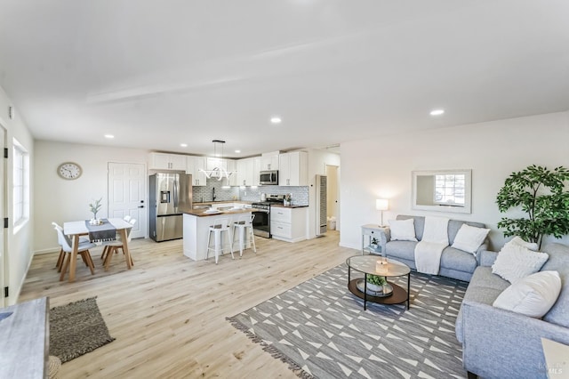 living room with a healthy amount of sunlight, sink, and light wood-type flooring