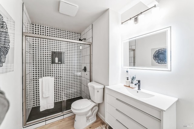 bathroom featuring vanity, wood-type flooring, a shower with door, and toilet