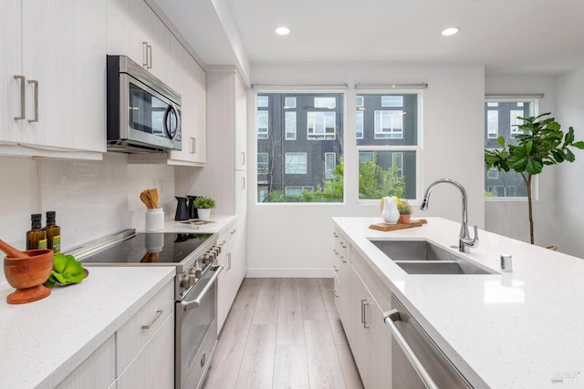 kitchen featuring appliances with stainless steel finishes, light stone counters, a wealth of natural light, and sink