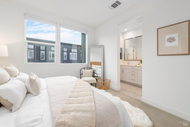 bedroom with light tile patterned floors, connected bathroom, and sink