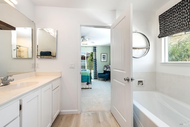 bathroom with ceiling fan, wood-type flooring, a tub to relax in, and vanity