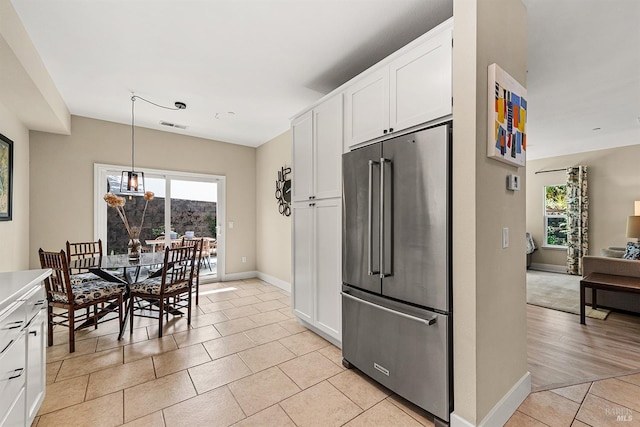 kitchen with white cabinetry, high end refrigerator, light tile patterned floors, and decorative light fixtures