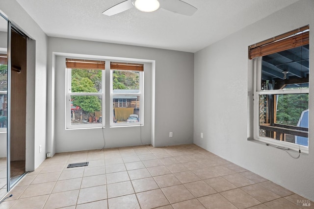 unfurnished room featuring light tile patterned floors, a textured ceiling, and ceiling fan