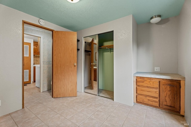 unfurnished bedroom featuring a closet, light tile patterned flooring, and a textured ceiling