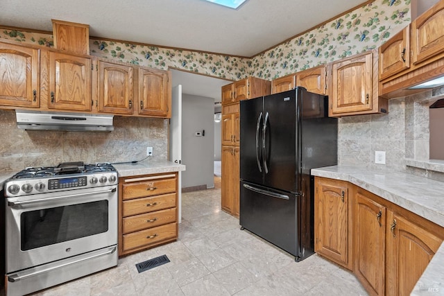 kitchen with decorative backsplash, black refrigerator, a textured ceiling, and high end stainless steel range