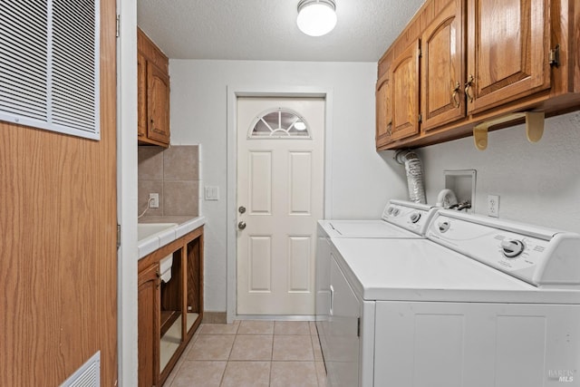 clothes washing area featuring cabinets, separate washer and dryer, a textured ceiling, and light tile patterned floors