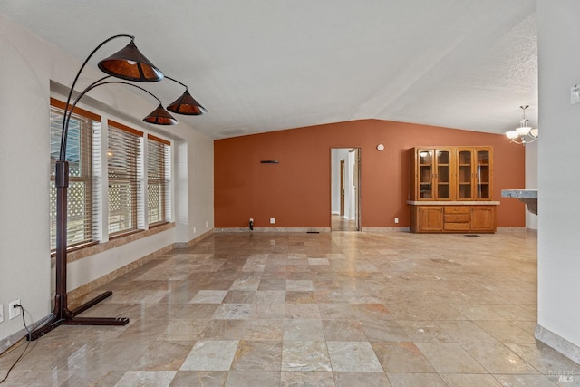 unfurnished living room with a notable chandelier and vaulted ceiling