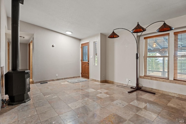 interior space with a wood stove and a textured ceiling