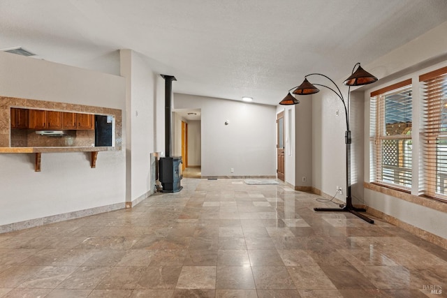 spare room with a wood stove, lofted ceiling, and a textured ceiling