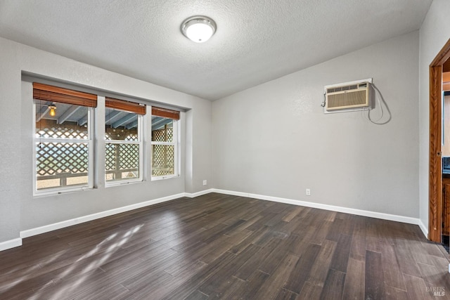 empty room featuring dark hardwood / wood-style flooring, a textured ceiling, a wall unit AC, and vaulted ceiling