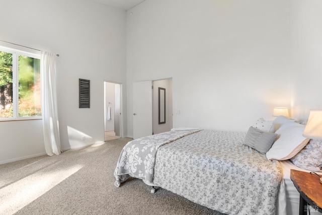 bedroom featuring carpet flooring, multiple windows, and a towering ceiling