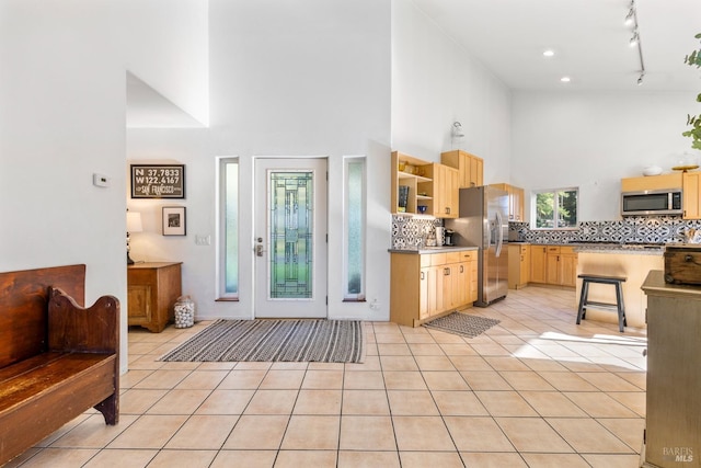 interior space with backsplash, light brown cabinets, light tile patterned floors, and stainless steel appliances