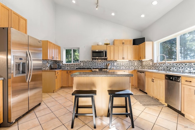 kitchen featuring a kitchen bar, a kitchen island, stainless steel appliances, and high vaulted ceiling