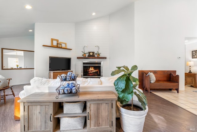 living room featuring a fireplace, dark tile patterned floors, and vaulted ceiling